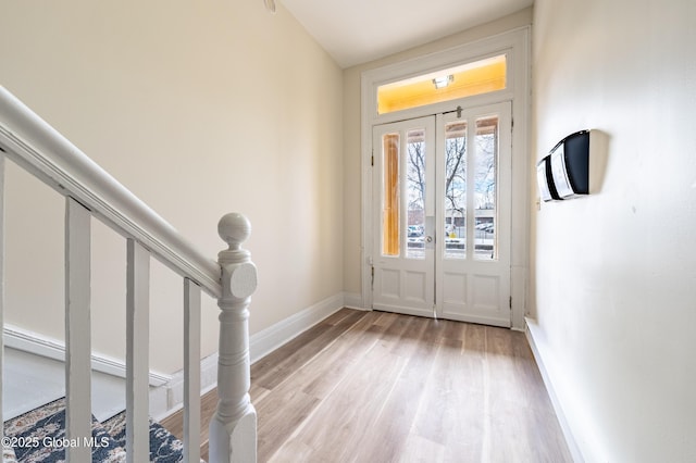 entrance foyer featuring light wood-type flooring, baseboards, and stairway