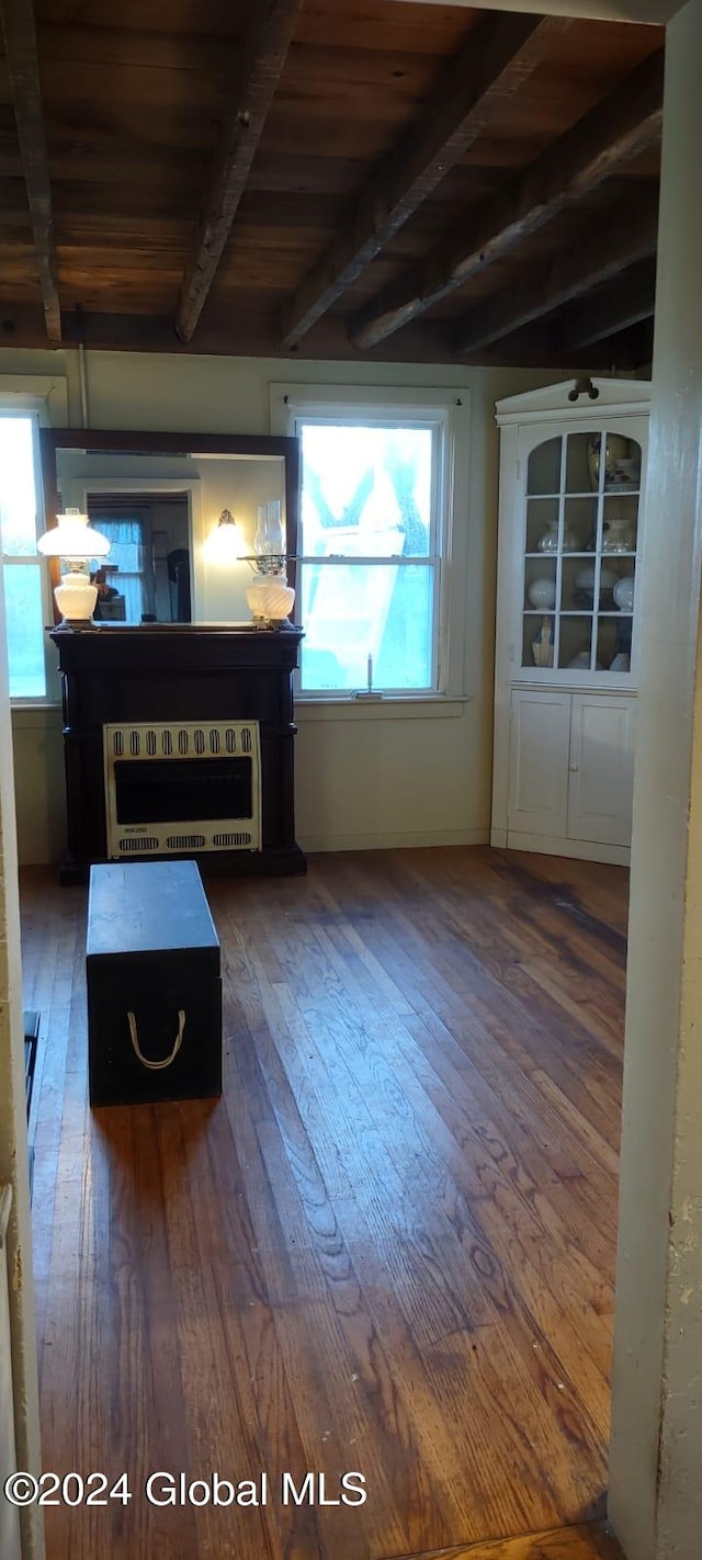 unfurnished living room featuring vaulted ceiling with beams, plenty of natural light, dark wood-type flooring, and wood ceiling