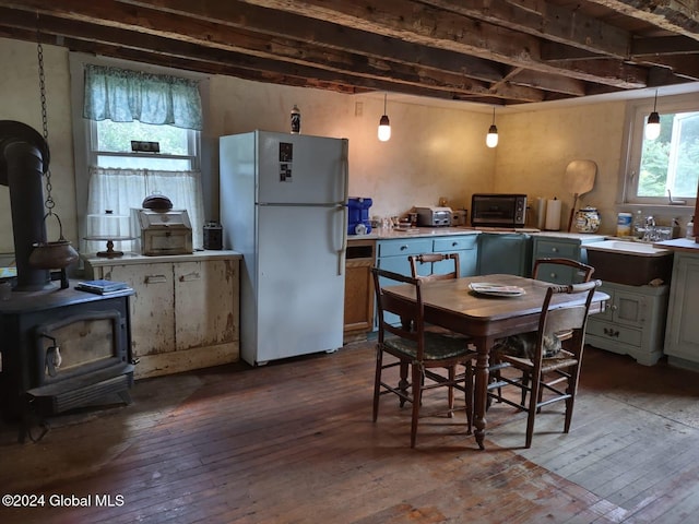 kitchen with white refrigerator, dark hardwood / wood-style floors, a wood stove, and sink