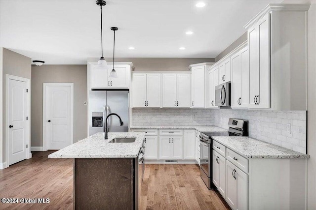 kitchen with white cabinetry, sink, hanging light fixtures, stainless steel appliances, and light hardwood / wood-style flooring