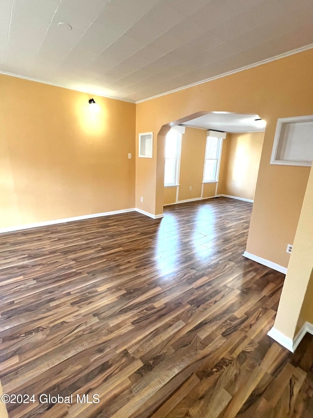 empty room featuring dark wood-type flooring and ornamental molding