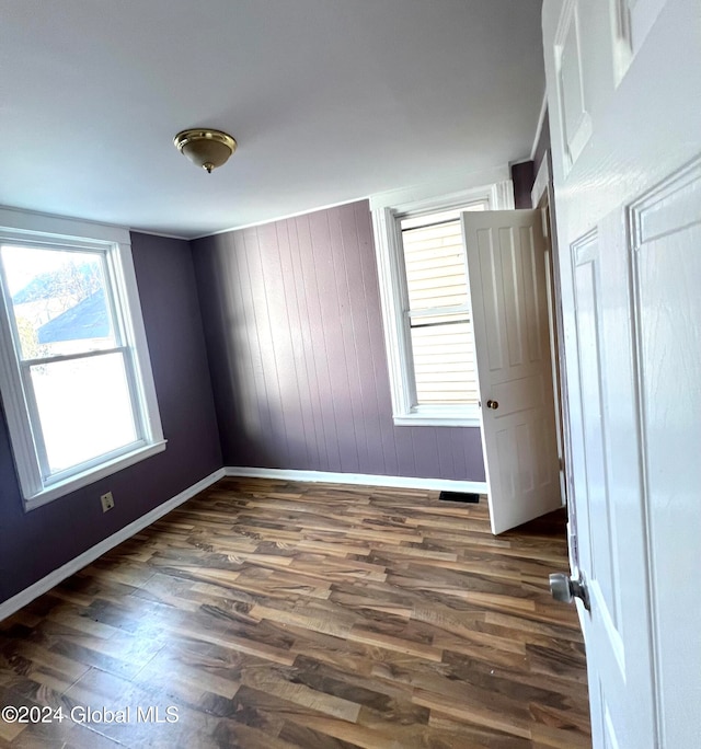 spare room featuring wooden walls and dark wood-type flooring