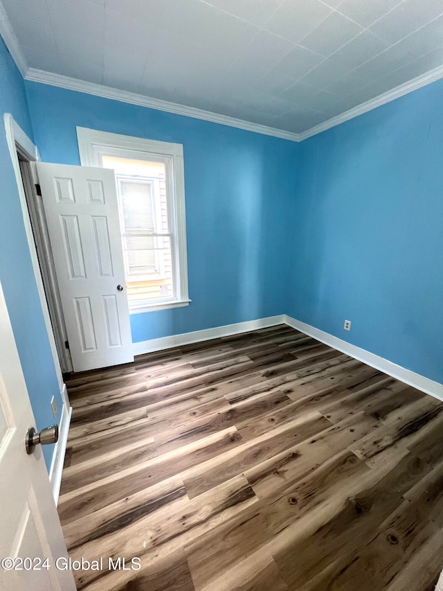 unfurnished room featuring ornamental molding and dark wood-type flooring