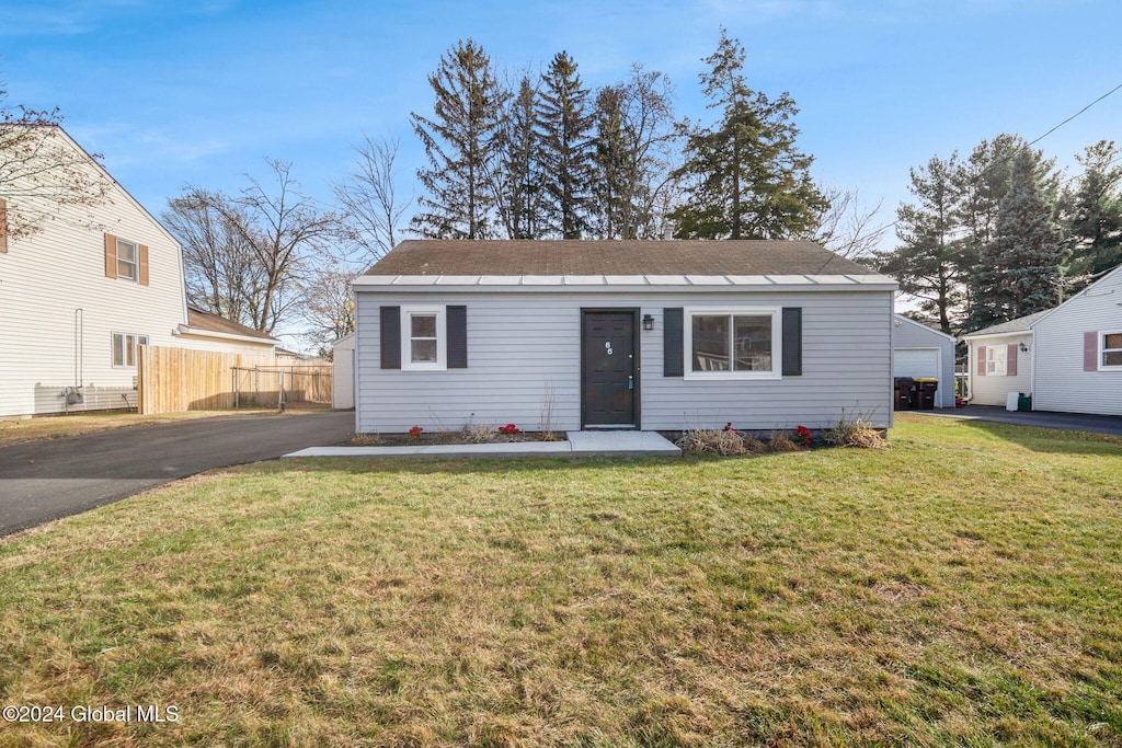 view of front of property featuring a garage, an outdoor structure, and a front lawn