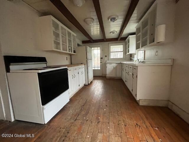 kitchen with white appliances, sink, beam ceiling, hardwood / wood-style floors, and white cabinetry