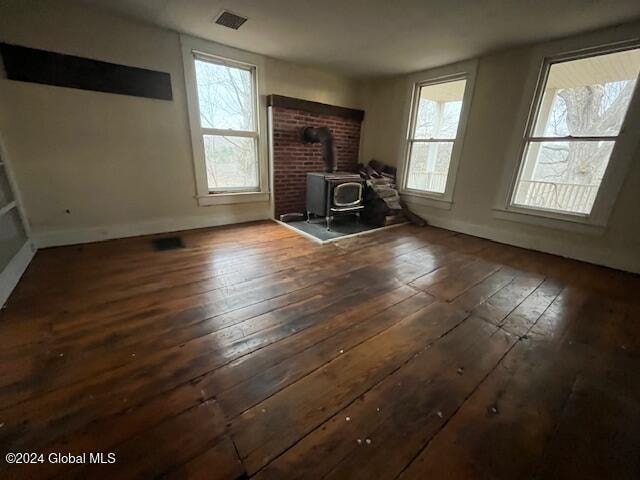 unfurnished living room with a wood stove and dark hardwood / wood-style floors