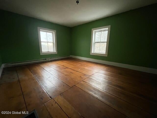 spare room with a wealth of natural light, hardwood / wood-style floors, and a baseboard heating unit