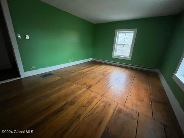 unfurnished room featuring wood-type flooring and baseboard heating