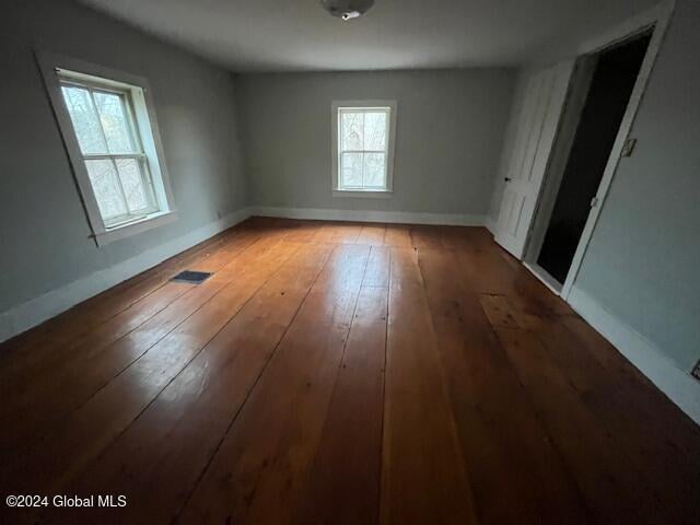 spare room with wood-type flooring and a healthy amount of sunlight