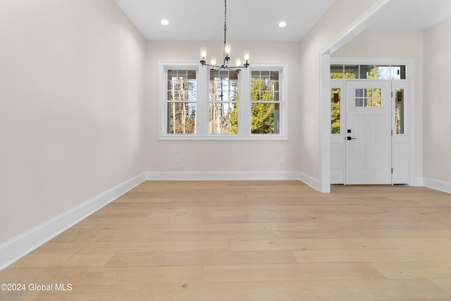 unfurnished dining area with a notable chandelier and light hardwood / wood-style flooring