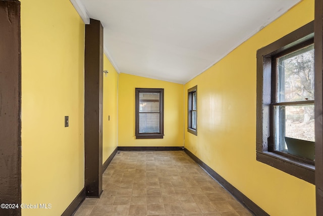 corridor with a wealth of natural light, crown molding, and vaulted ceiling