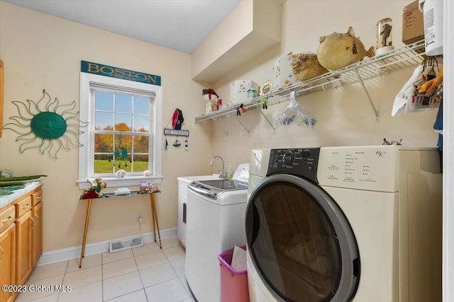 washroom featuring washer and clothes dryer, light tile patterned flooring, and cabinets