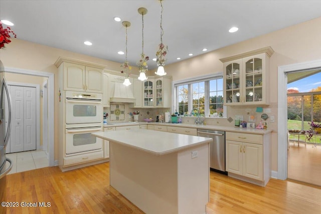 kitchen with dishwasher, a kitchen island, plenty of natural light, and light wood-type flooring