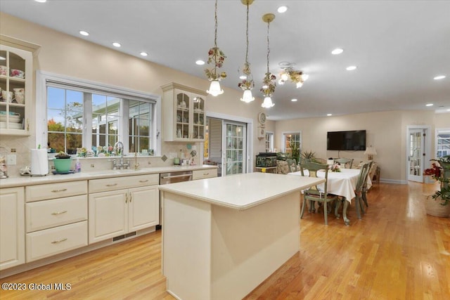 kitchen with light wood-type flooring, tasteful backsplash, pendant lighting, a chandelier, and a kitchen island