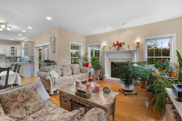 living room featuring light wood-type flooring, sink, and a tiled fireplace