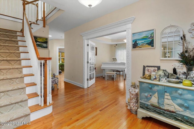 entryway with light hardwood / wood-style floors and a raised ceiling