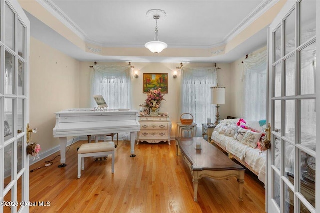 living area with crown molding, light hardwood / wood-style flooring, and a tray ceiling