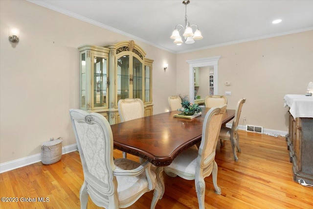 dining room featuring a chandelier, light wood-type flooring, and ornamental molding