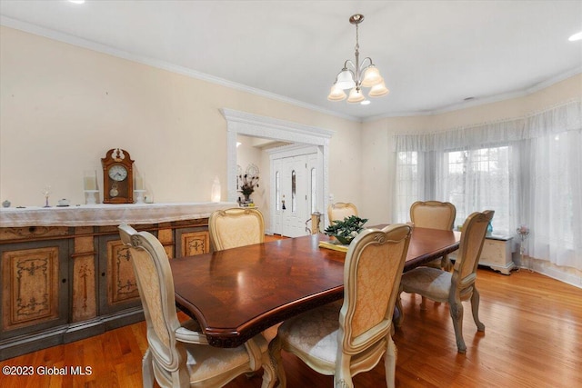 dining area featuring wood-type flooring, an inviting chandelier, and crown molding