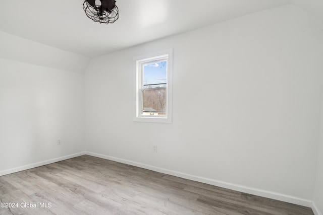 spare room featuring lofted ceiling and light hardwood / wood-style flooring