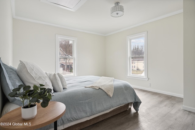 bedroom featuring multiple windows, hardwood / wood-style floors, and ornamental molding