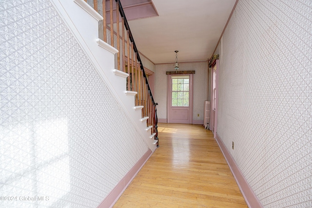 corridor featuring ornamental molding, radiator heating unit, and light wood-type flooring