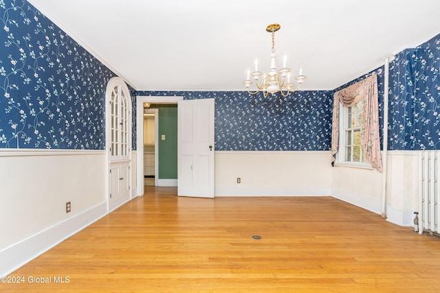 empty room with ornamental molding, hardwood / wood-style floors, and an inviting chandelier