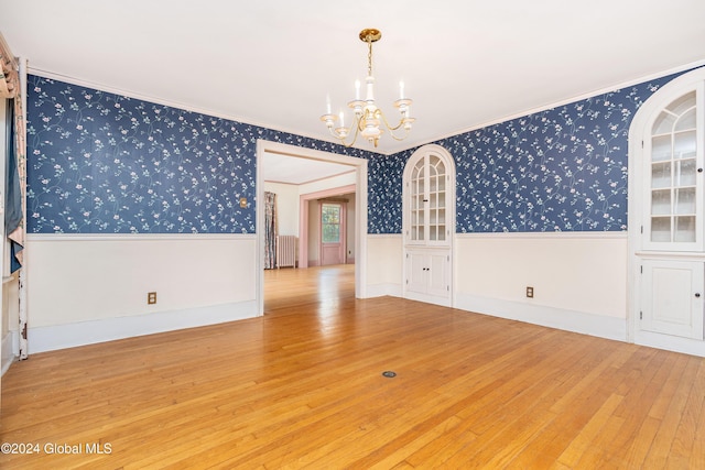 unfurnished room featuring hardwood / wood-style floors, crown molding, radiator heating unit, and a chandelier