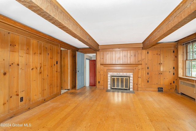 unfurnished living room with hardwood / wood-style flooring, radiator heating unit, beamed ceiling, and wood walls