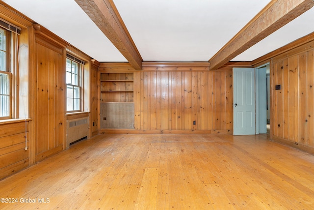 unfurnished living room featuring radiator, wooden walls, beamed ceiling, and light wood-type flooring