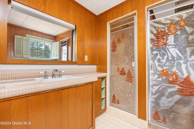 bathroom with sink, crown molding, tile patterned flooring, wooden walls, and decorative backsplash