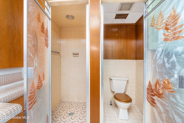 bathroom featuring a tile shower, tile walls, and toilet