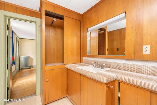 bathroom with vanity, radiator heating unit, backsplash, and wooden walls