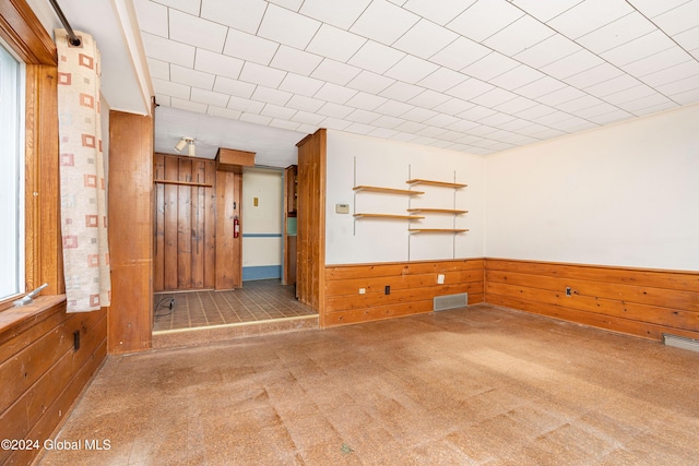 unfurnished room with carpet floors and wooden walls