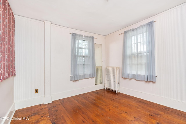 spare room with hardwood / wood-style flooring, radiator, and a wealth of natural light