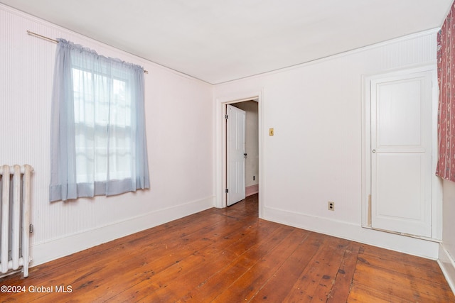 unfurnished room featuring radiator and dark hardwood / wood-style floors