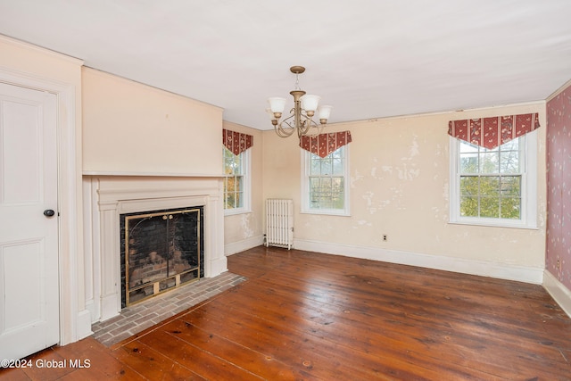 unfurnished living room with radiator, a chandelier, dark hardwood / wood-style floors, and a healthy amount of sunlight