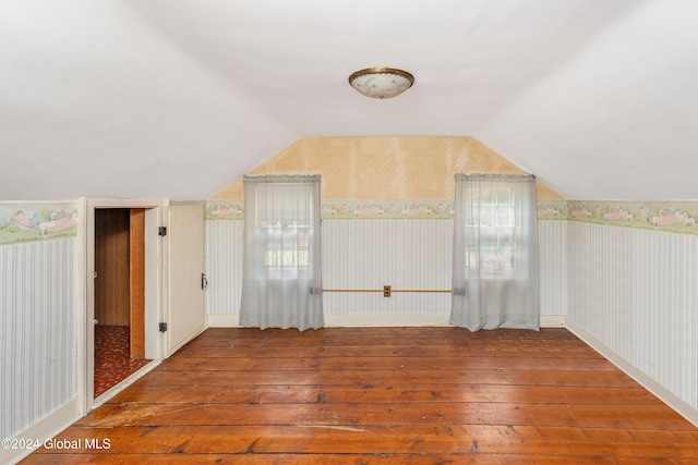 additional living space with hardwood / wood-style flooring and lofted ceiling