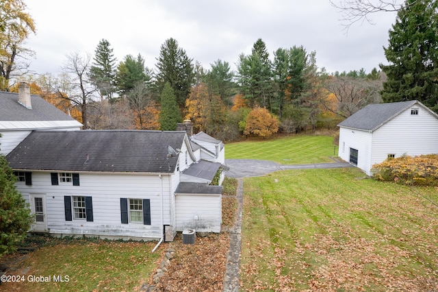 view of side of home with cooling unit, a garage, a lawn, and an outdoor structure