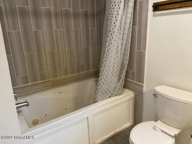 bathroom featuring shower / tub combo and toilet