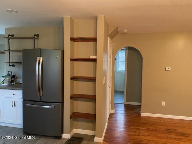 kitchen with stainless steel fridge, dark hardwood / wood-style flooring, and white cabinetry