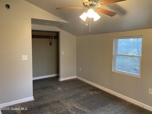 unfurnished bedroom featuring dark carpet, a closet, vaulted ceiling, and ceiling fan