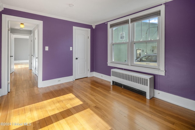 spare room with hardwood / wood-style floors, radiator heating unit, and ornamental molding