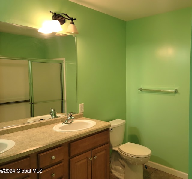 bathroom featuring tile patterned floors, vanity, toilet, and an enclosed shower