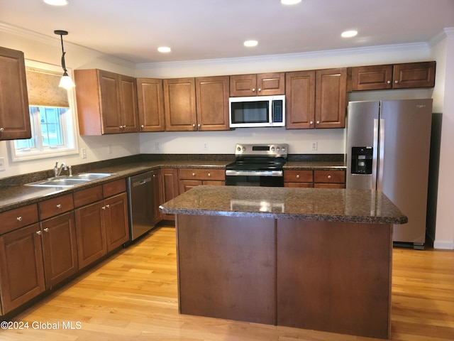 kitchen featuring a kitchen island, crown molding, appliances with stainless steel finishes, and light hardwood / wood-style flooring