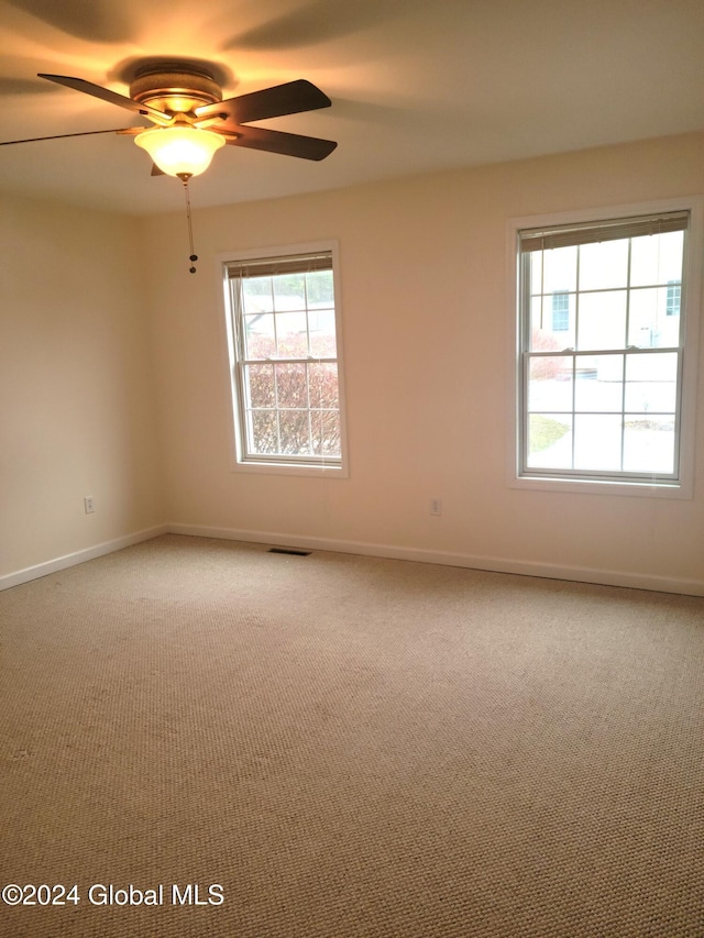 carpeted spare room featuring ceiling fan