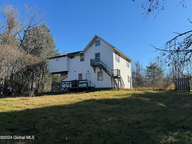 rear view of house with a wooden deck and a lawn