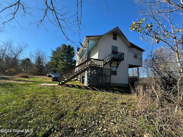 view of side of property with a lawn and a balcony