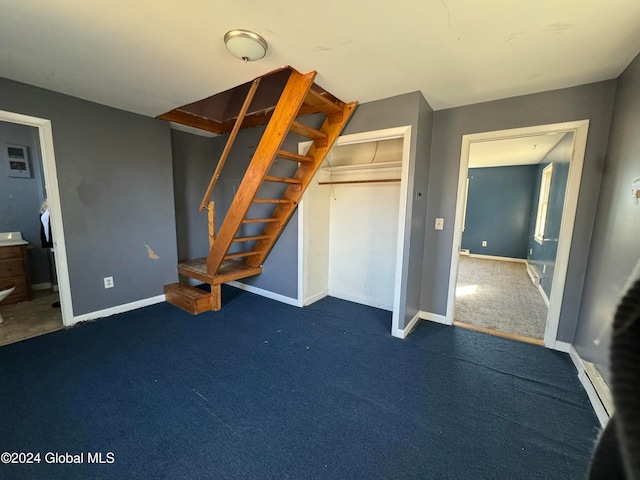 interior space featuring a closet, dark carpet, and a baseboard heating unit