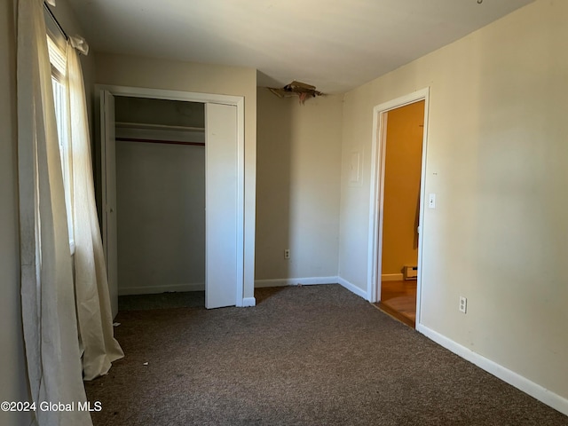 unfurnished bedroom featuring carpet floors, baseboard heating, and a closet